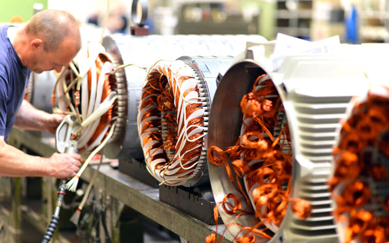 Mitarbeiter im Maschinenbau bestückt die Statoren von großen Elektromotoren mit der nötigen Verkabelung